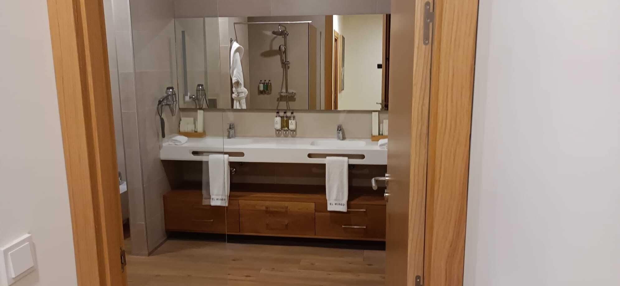 Un baño con tocador de madera, un espejo y ducha.