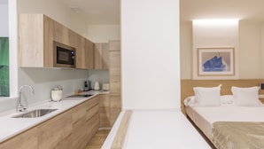 A modern hotel room with a kitchenette, a bed with white bedding, and a framed picture on the wall. - Graffiti Suites El Museo (Málaga)