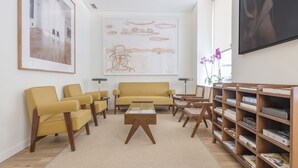A modern living room with a sofa, chairs, a coffee table, and a bookshelf. - Graffiti Suites El Museo (Málaga)