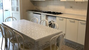 Cocina compacta con alacenas blancas, una mesa de comedor con sillas y un microondas integrado.
