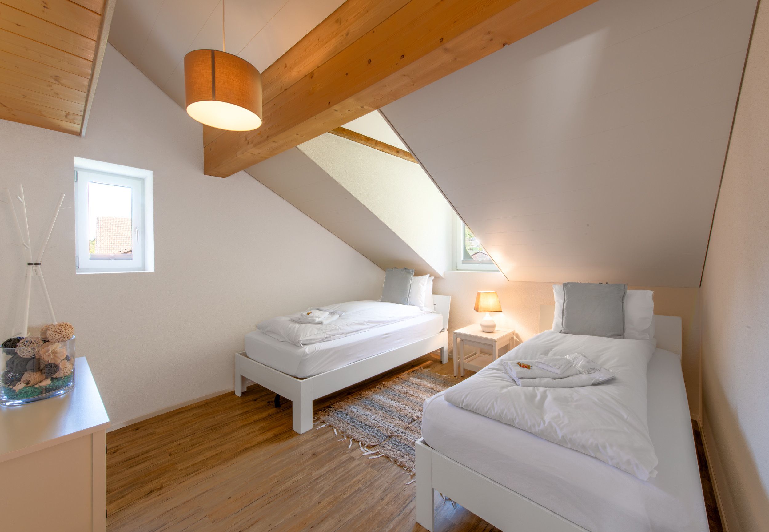 Ein Schlafzimmer mit zwei Betten, einer Holzbalkendecke und einem Fenster.