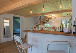 A modern kitchen with a wooden island, wine glasses, and bottles. - Le Manoir Penthouse - spacious, new and central location (Wengen)