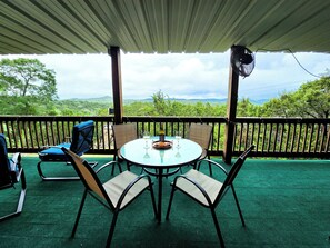 Un espace extérieur abrité, avec une table et des chaises, offrant une vue sur un paysage pittoresque.
