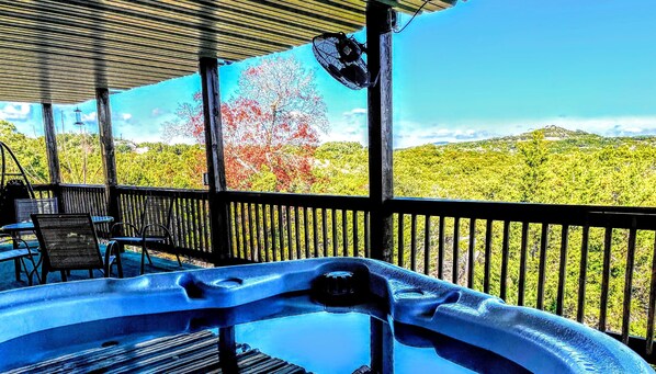 Un bain à remous sur une terrasse en bois, avec vue sur un paysage boisé.