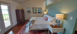 Een slaapkamer met een bed, twee bedlampen, een nachtkastje, een kamerkleed met dessin en drie posters aan de muur.