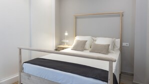 A neatly arranged bedroom with a bed, bedside table, and lamp. - Two bedroom apartment with garden - DDS ONS (Vigo)