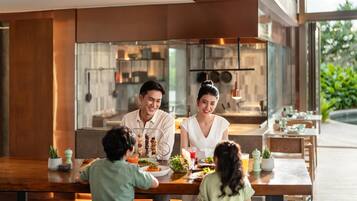 Una familia cenando en un restaurante con una decoración moderna, ventanas amplias y una zona de cocina a la vista.