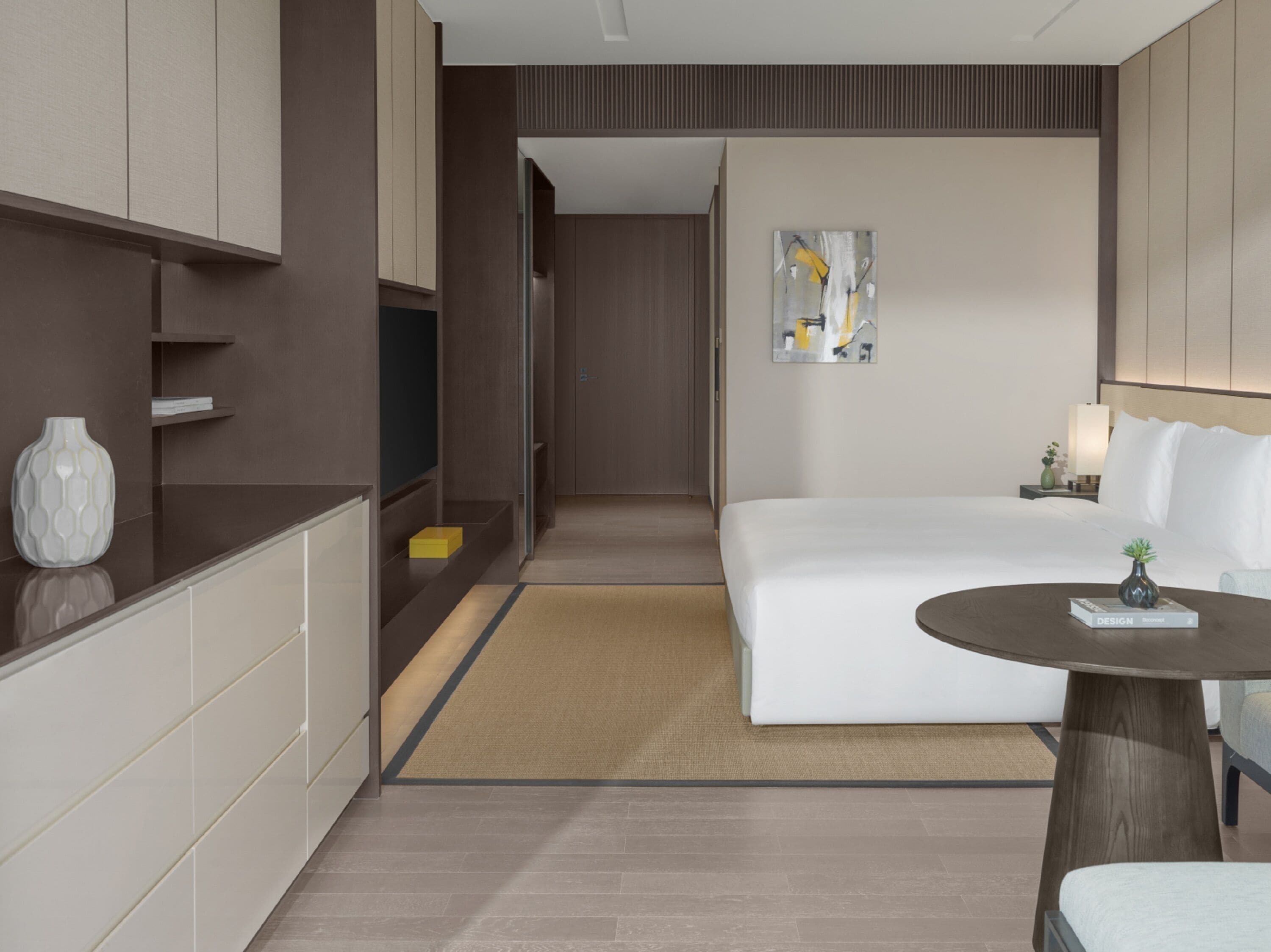 Una habitación de hotel moderna con cama, mesita de noche y un pequeño rincón de descanso.