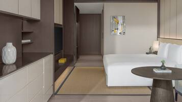 Una habitación de hotel moderna con cama, mesita de noche y un pequeño rincón de descanso.