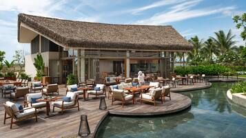 Een resort met een zwembad, terras en een gebouw met rieten dak.