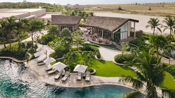 Un complexe hôtelier doté d’une piscine, de chaises longues et d’un restaurant.