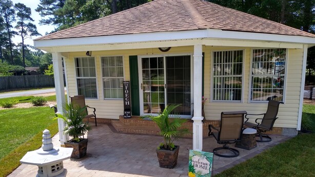 A small, single-story building with a porch, a seating area with chairs and a table, and a welcome sign. - Home AWAY FROM HOME!!! Franklin, VA<br>(1 BEDROOM) (Franklin)