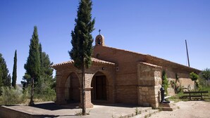 A small brick building with a bell tower, arched entrance, and a bench outside. - La Boutique Espacio Rural (Rural, Gastronomic, Playful Experiences, etc ...) (Nuévalos)