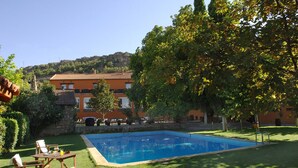 A swimming pool with a wooden deck, surrounded by well-maintained grass and trees. - La Boutique Espacio Rural (Rural, Gastronomic, Playful Experiences, etc ...) (Nuévalos)
