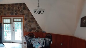 A dining area with a stone wall, a chandelier, and a tiled floor. - Quiet Waterfront Home (Waddington)