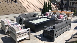 Une terrasse extérieure comprenant un canapé d’angle, un foyer et un espace repas.