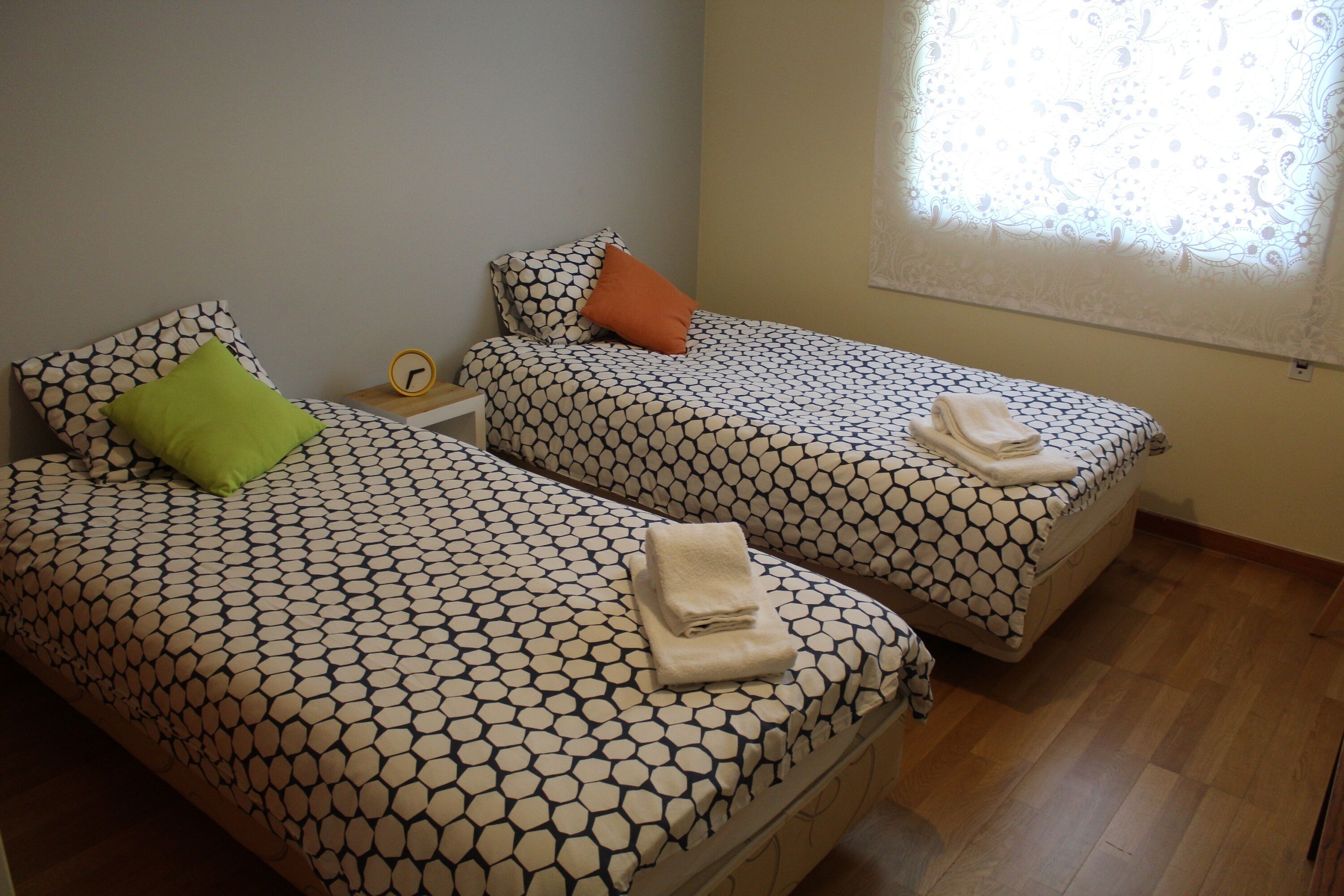 A room with two beds, each with patterned bedding and pillows.