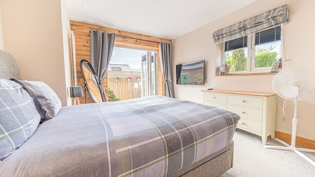 A bedroom with a bed, a TV, a desk, and a window with curtains. - 1 bedroom accommodation in Ulverston (Ulverston)