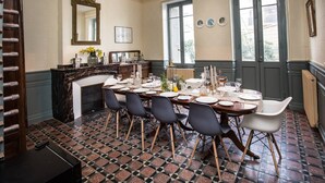 Un comedor con una mesa grande dispuesta para seis personas, una chimenea y vistas a través de las ventanas.
