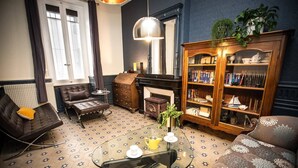 Una sala de estar acogedora con chimenea, sofás de cuero, una mesa de centro de vidrio y una estantería de madera.