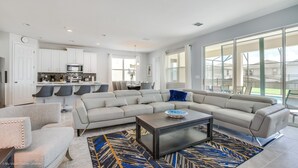 A modern living room with a large sectional sofa, a coffee table, and a patterned rug.