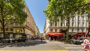 A cobblestone street lined with multi-story buildings, including a hotel with a red awning and a visible sign for 'Le Week End'. - Madeleine- Charming, quiet, upscale apartment - 2 bedrooms 6 people (Paris)