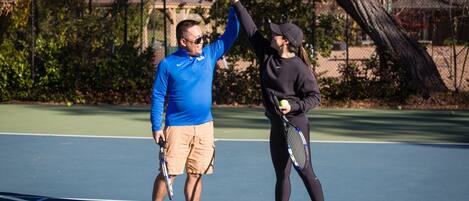 Una cancha de tenis con dos personas, una dándole un choque de manos a la otra.