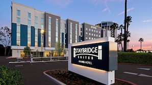 A Staybridge Suites Aning Hotel sign with a modern building in the background.