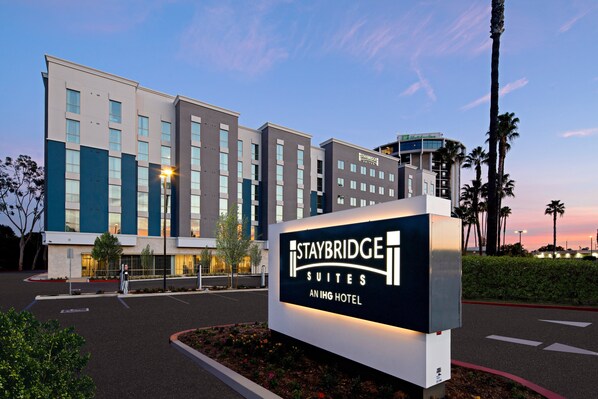 Señal de Staybridge Suites Aning Hotel, con un edificio moderno de fondo.