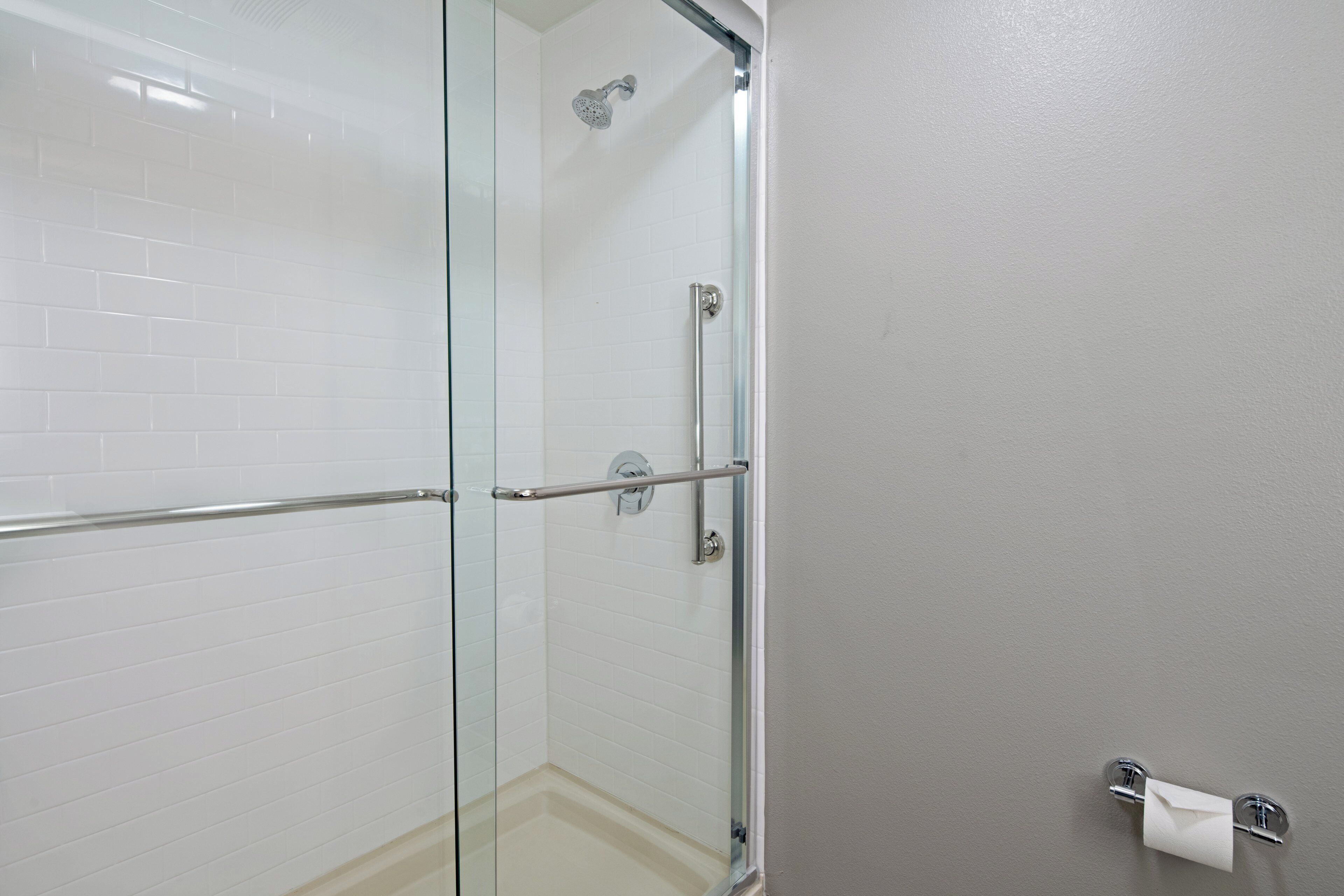 A glass-enclosed shower with a metal handle and a towel rack.
