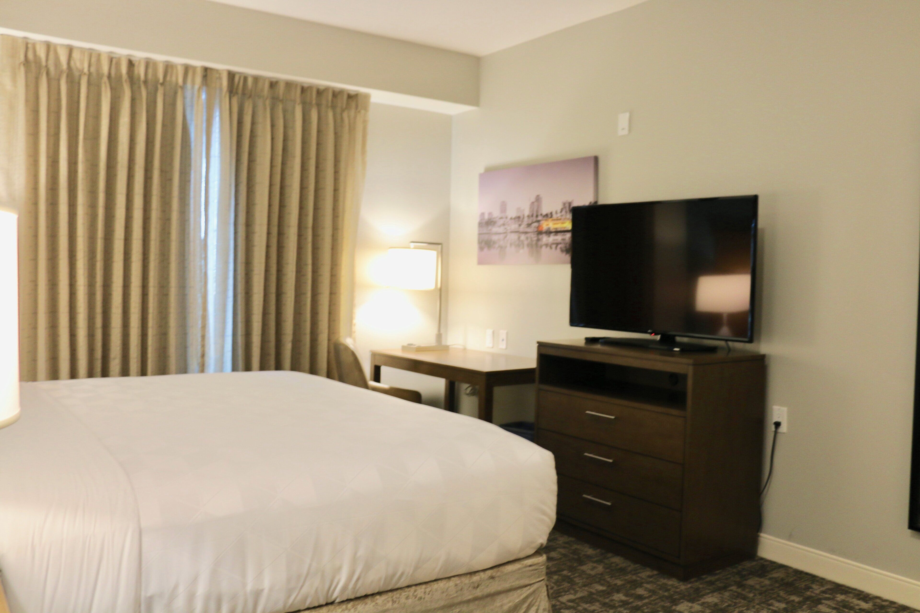 Une chambre d’hôtel avec un lit, un bureau, une télévision et une lampe.