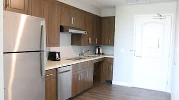 Una cocina moderna con electrodomésticos de acero inoxidable, armarios de madera y encimera blanca.