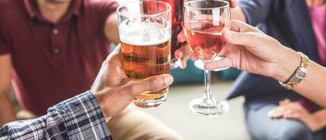 Een groep mensen die met bierglazen en wijnglazen proosten in een informele setting.