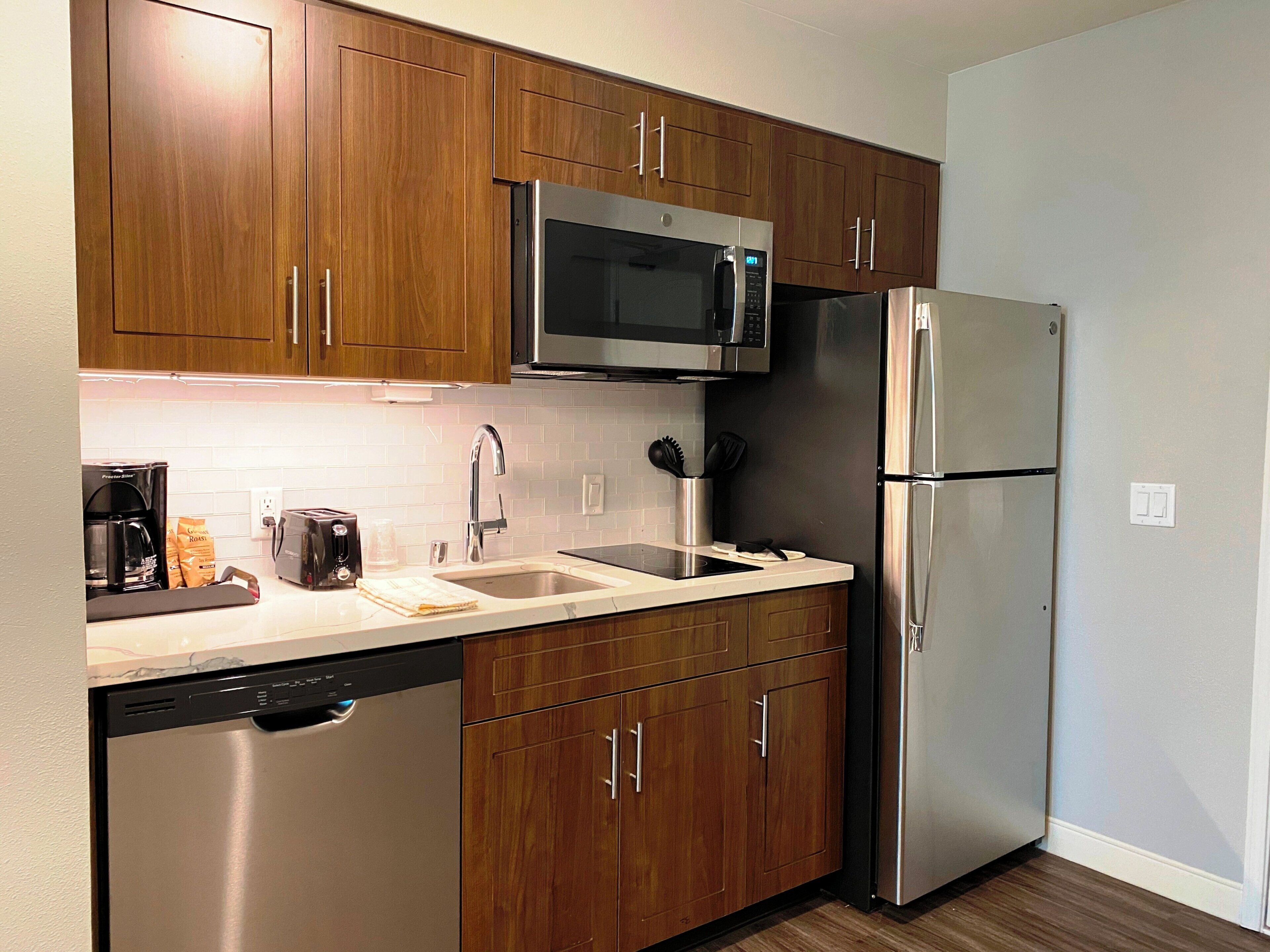 A modern kitchen with wooden cabinets, stainless steel appliances, a dishwasher, and a coffee maker.