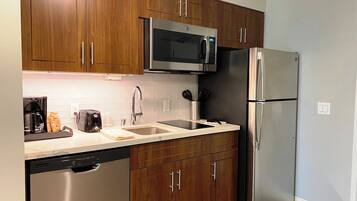 A modern kitchen with wooden cabinets, stainless steel appliances, a dishwasher, and a coffee maker.