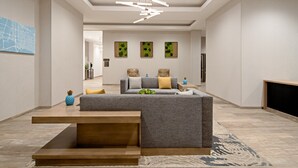 A modern living room with a sectional sofa, a coffee table, and a fireplace. There are three wall-mounted art pieces and a map on the wall.