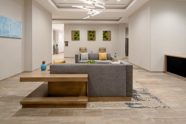 Un salon moderne avec un canapé d’angle, une table basse et une cheminée. Trois œuvres d’art sont accrochées au mur, ainsi qu’une carte.