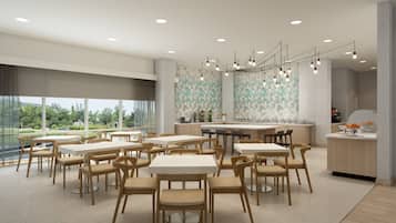 A modern dining area with multiple tables and chairs, a central bar, and a view of greenery outside.