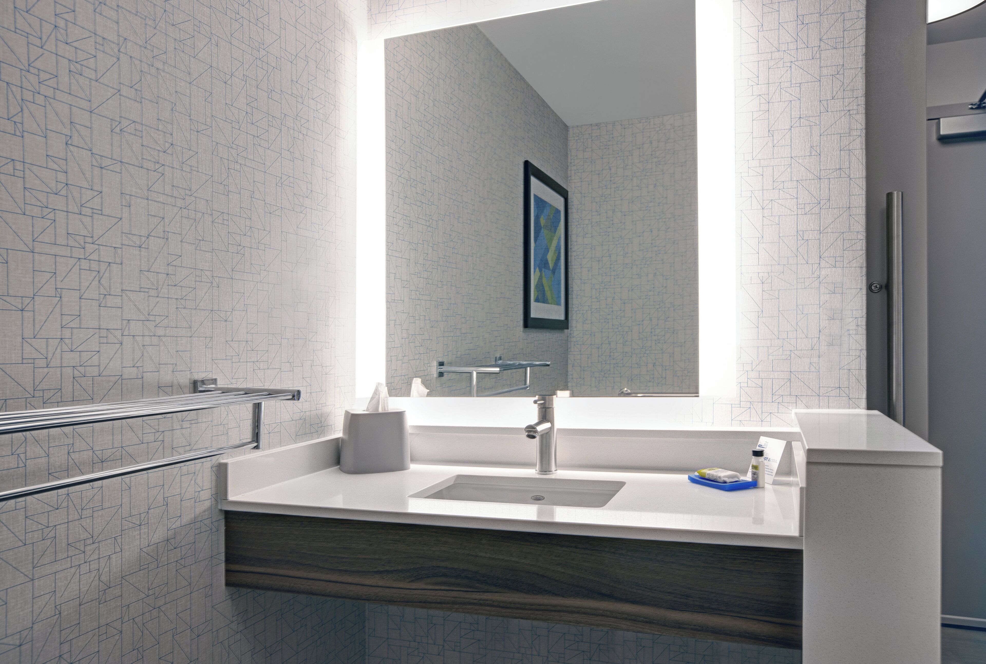 A modern bathroom with a large mirror, a sink, and a towel rack.