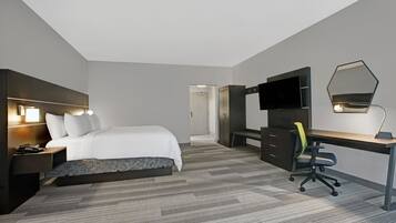 Une chambre d’hôtel avec un lit, un bureau, une télévision et un miroir.