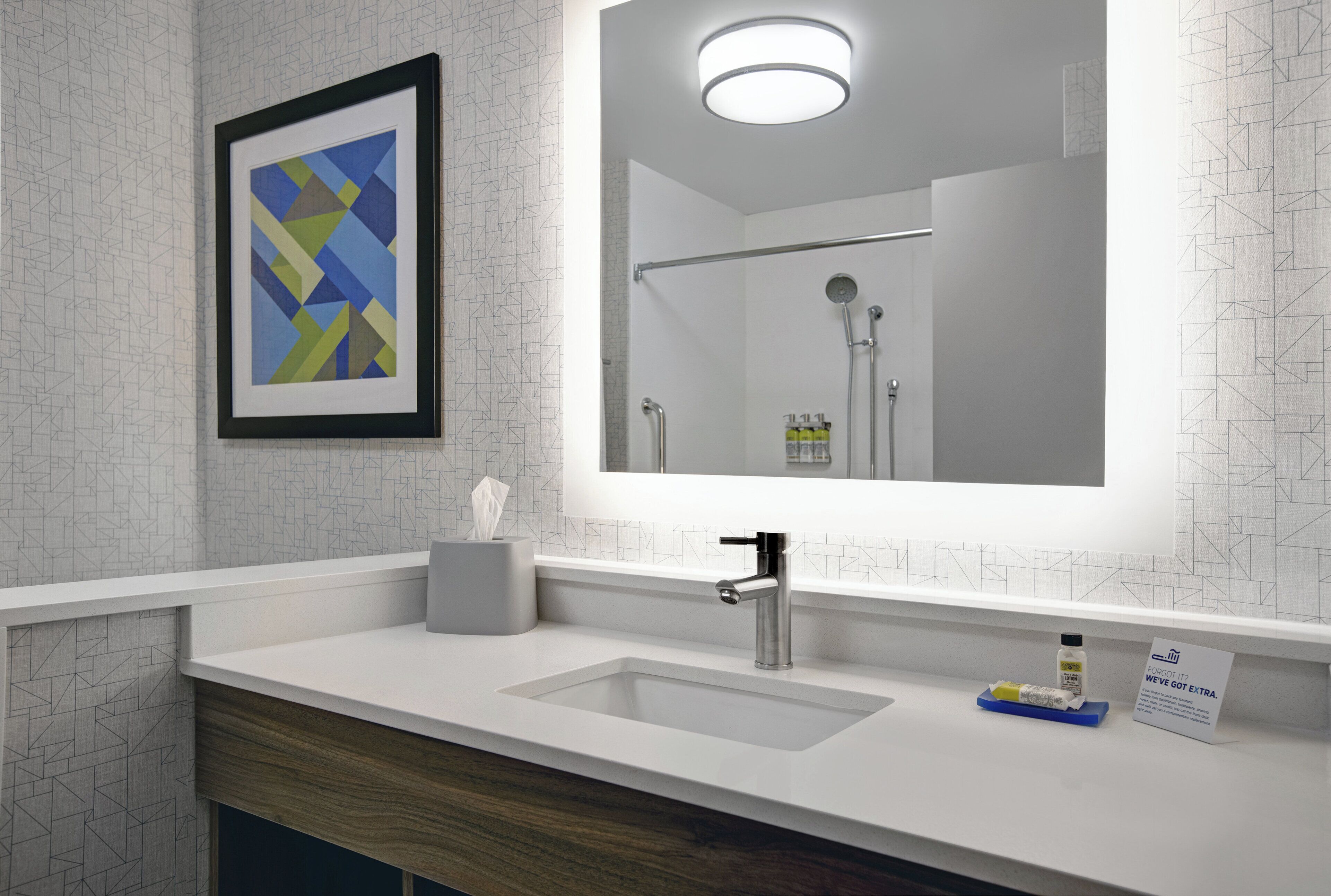 Un baño moderno con un espejo grande, un lavamanos y una ducha.