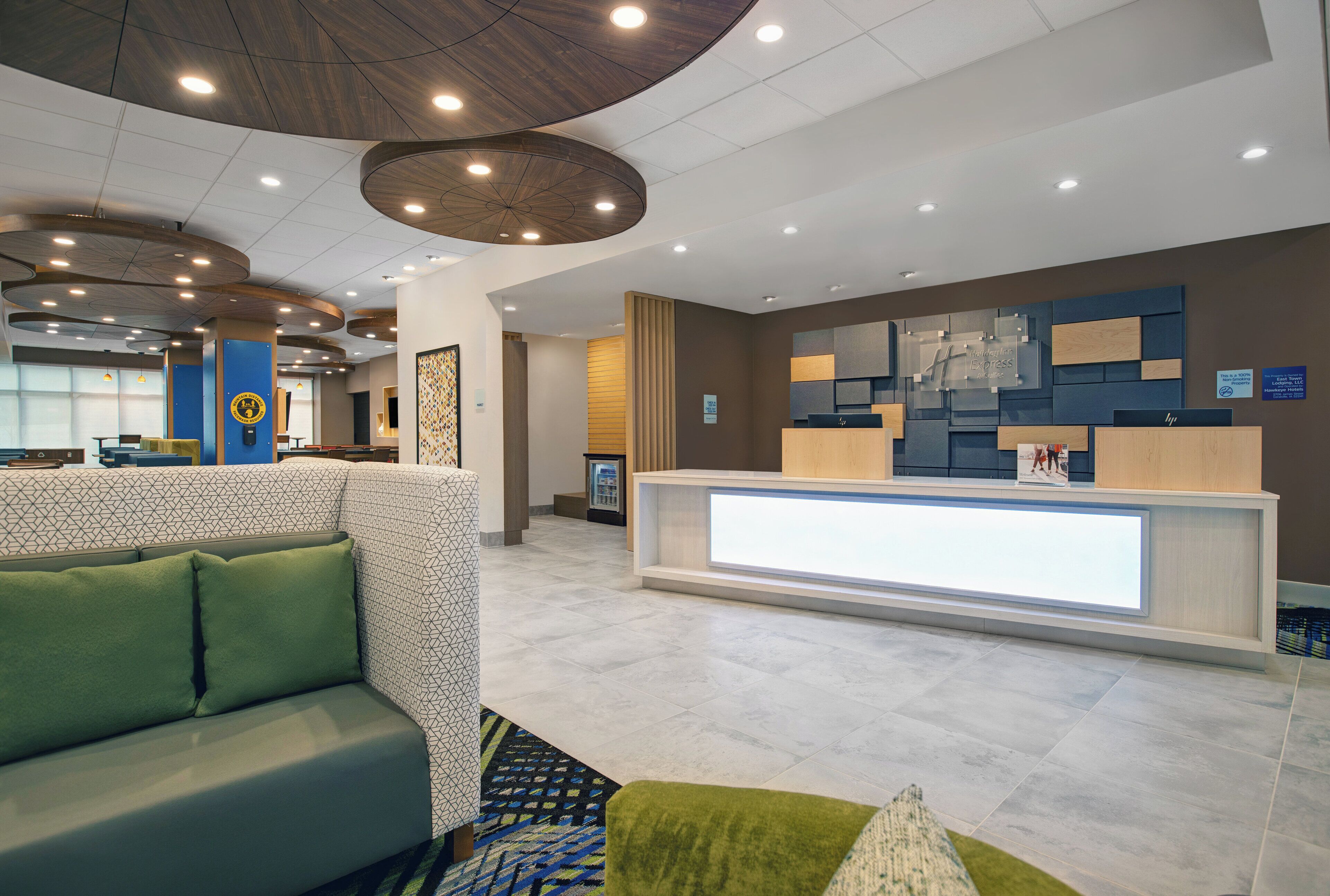 Un hall d’hôtel moderne avec un comptoir d’accueil, un espace salon et un mur décoré de motifs.