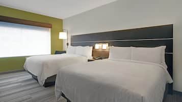 Una habitación de hotel con dos camas, una mesita de noche con lámpara y una ventana con persianas.