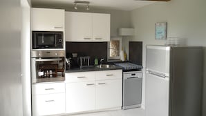 Une cuisine moderne avec des meubles blancs, un réfrigérateur en acier inoxydable, un four à micro-ondes et un lave-vaisselle.