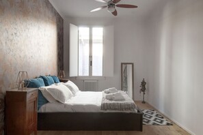 A bedroom with a bed, a dresser, a ceiling fan, a window, and a radiator. - UR-NEST Testoni, Elegant and quaint two bedroom (Bologna)