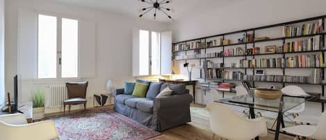 Una sala de estar con sofá, sillas, una mesa de centro, una estantería y un candelabro.