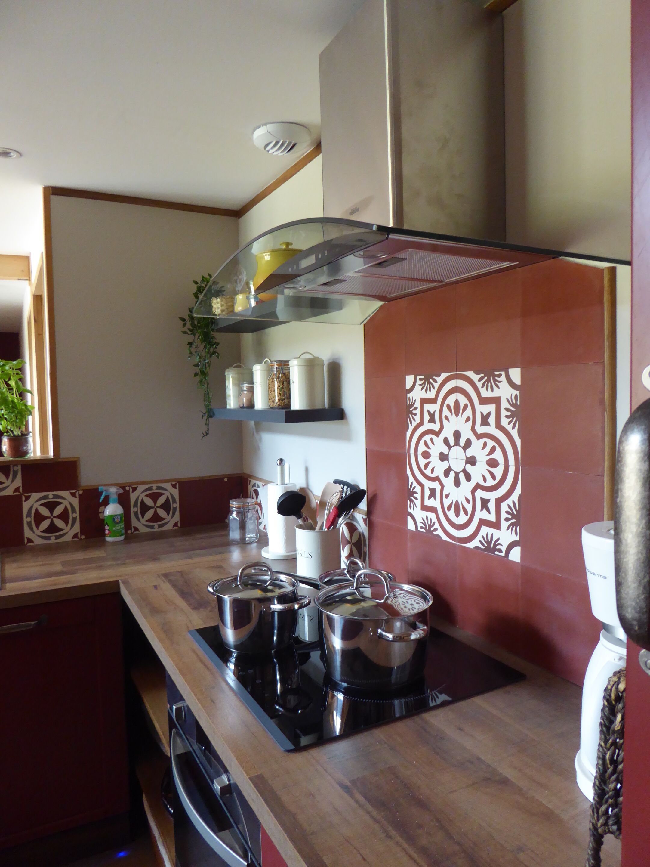 Una cocina con estufa, ollas, cafetera y un salpicadero decorativo.
