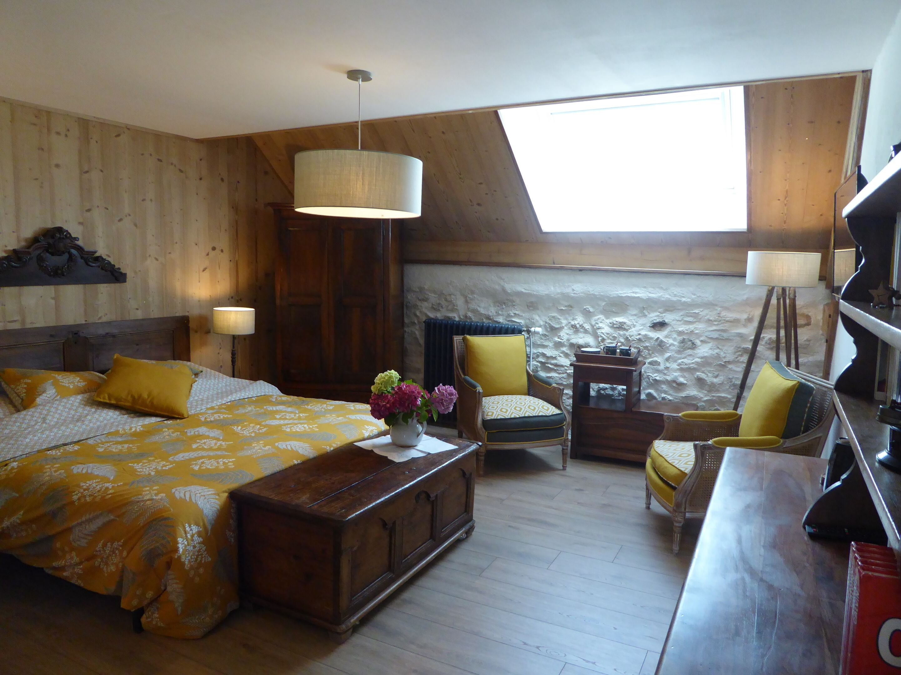 Een kamer met een bed, een houten kist, een stoel, een tafel en een lamp.