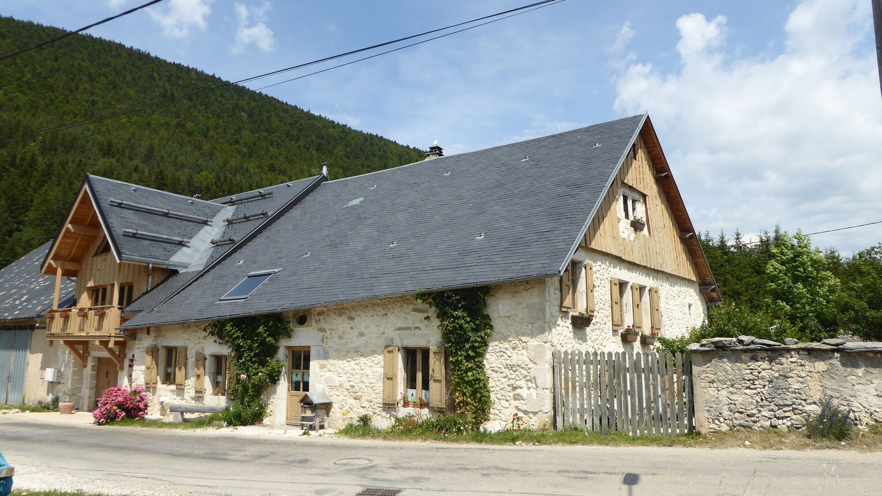 A stone building with a sloped roof, wooden balconies, and a stone wall.