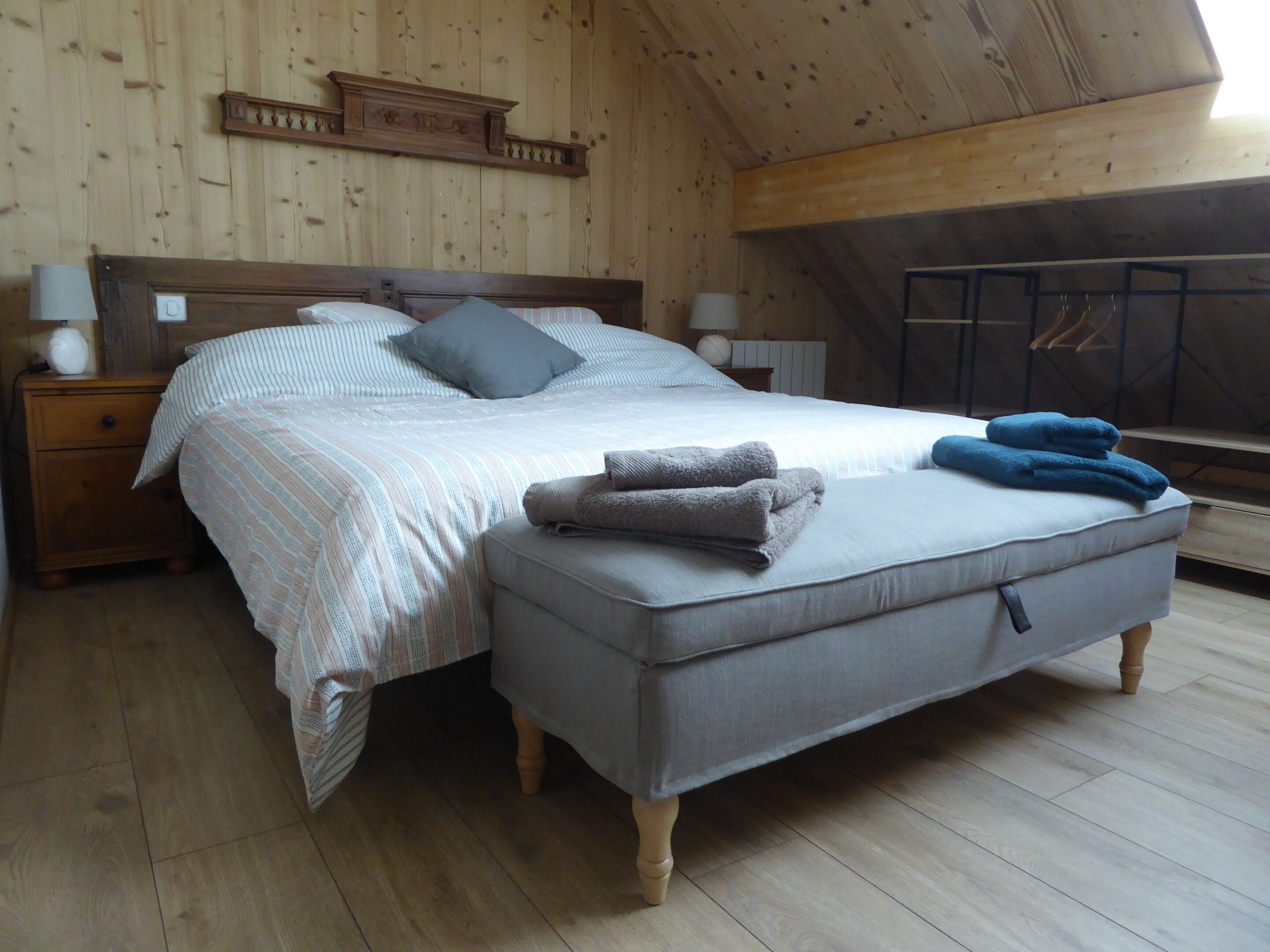 Ein Schlafzimmer mit Bett, Nachttischen, einer Bank und einem Wandregal.